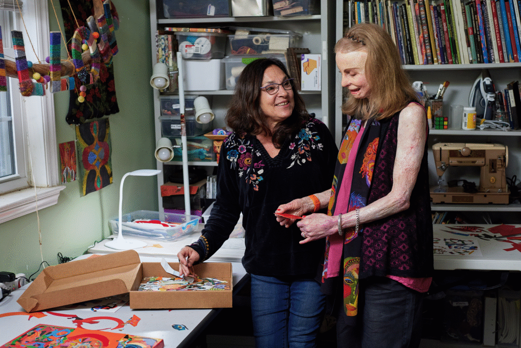 Charlene Pell pictured admiring the exquisite silk scarf artist Judi Magier created with the mosaic of faces. - photo Joey Seawell